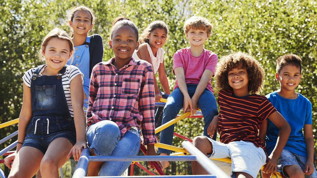 Pre-teen friends sitting on climbing frame in playground