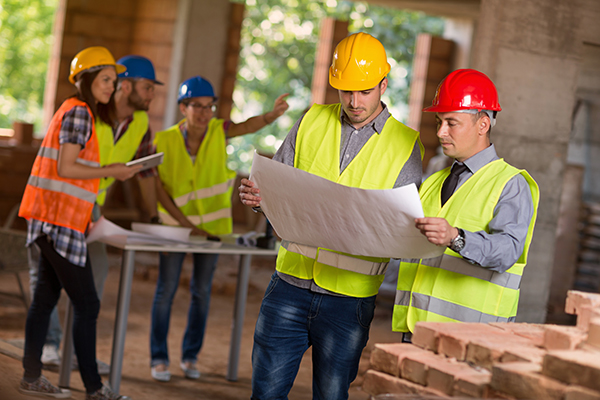 Investiture and architect look on building plan at construction site